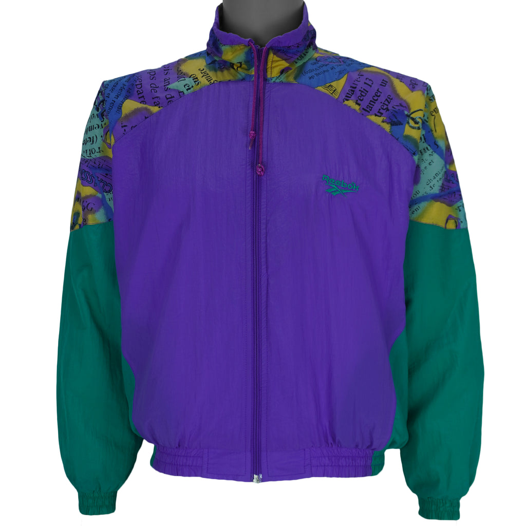 1990s vintage Reebok colorblock, zip-up windbreaker. Purple and green colorblock with multicolor pattern on yolk and 1/4 of sleeves. Medium in size and is in excellent condition.