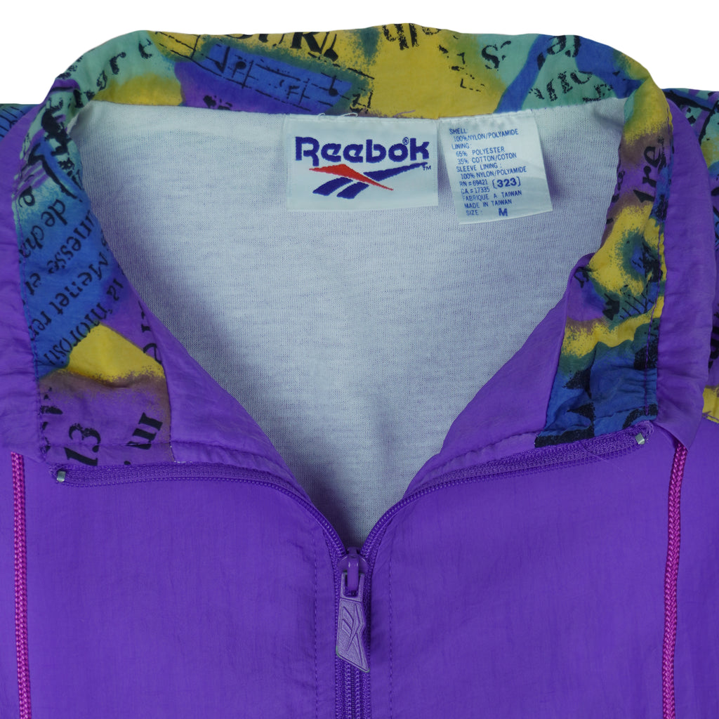 1990s vintage Reebok colorblock, zip-up windbreaker. Purple and green colorblock with multicolor pattern on yolk and 1/4 of sleeves. Medium in size and is in excellent condition.