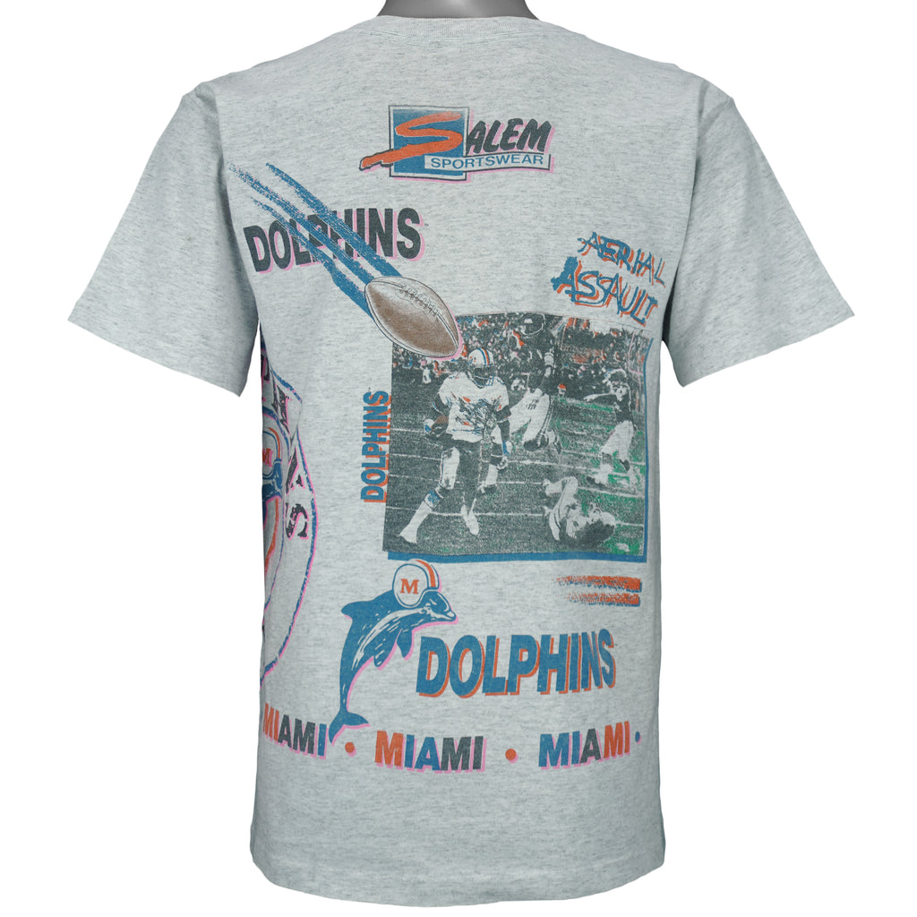 1990 vintage NFL Miami Dolphins, Aerial Assault, all-over-print T-Shirt by Salem Sportswear. Grey in color, fits Medium in size and is in excellent condition.