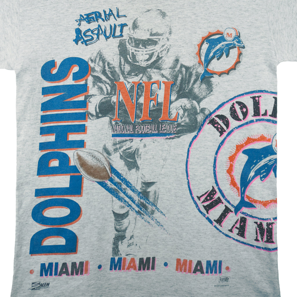 1990 vintage NFL Miami Dolphins, Aerial Assault, all-over-print T-Shirt by Salem Sportswear. Grey in color, fits Medium in size and is in excellent condition.