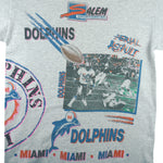 1990 vintage NFL Miami Dolphins, Aerial Assault, all-over-print T-Shirt by Salem Sportswear. Grey in color, fits Medium in size and is in excellent condition.