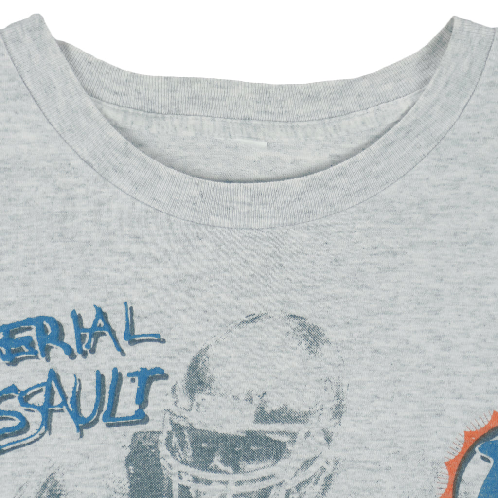 1990 vintage NFL Miami Dolphins, Aerial Assault, all-over-print T-Shirt by Salem Sportswear. Grey in color, fits Medium in size and is in excellent condition.