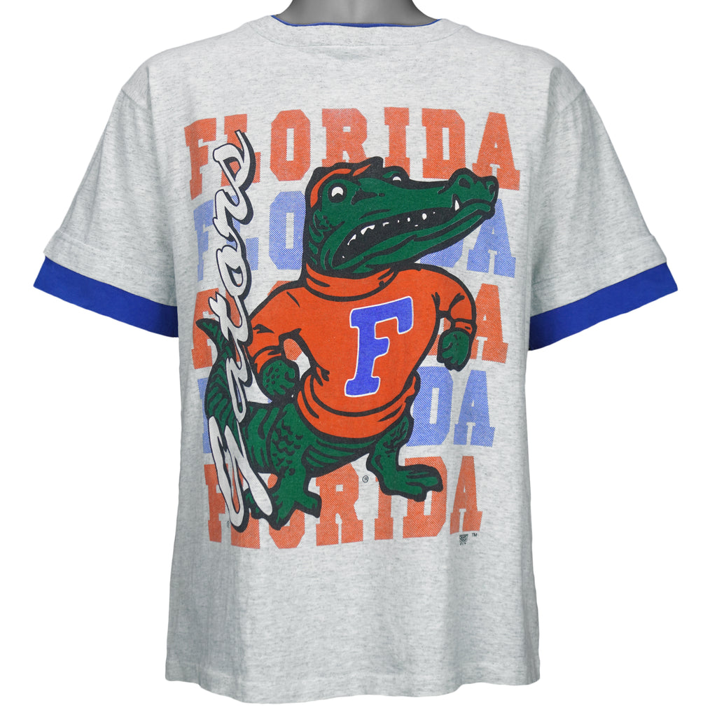 1990s vintage NCAA University of Florida Gators underlayer T-Shirt by Tee's Unlimited. Grey in color with blue sleeves, spell-out and logo on the front, Medium in size and is in excellent condition.