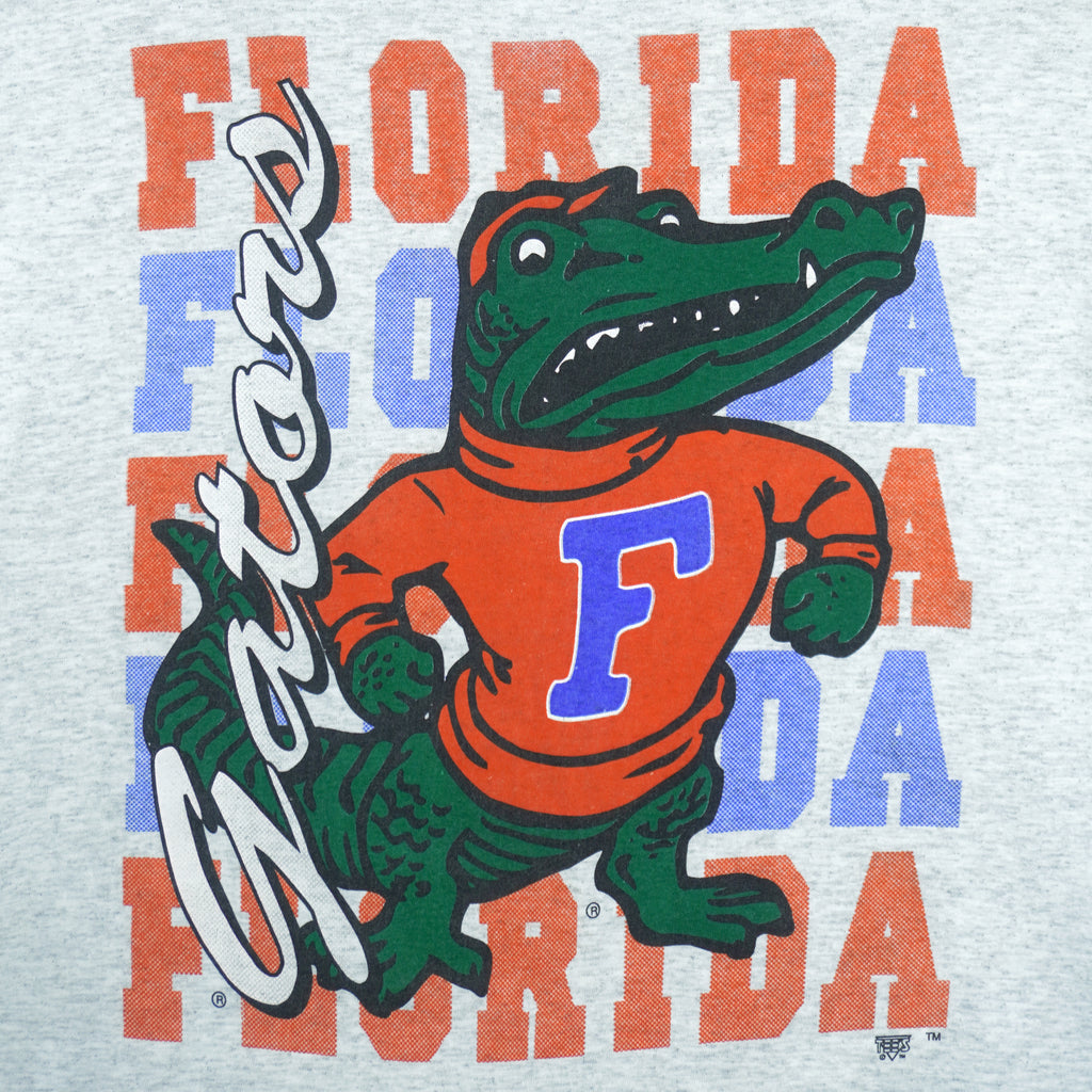 1990s vintage NCAA University of Florida Gators underlayer T-Shirt by Tee's Unlimited. Grey in color with blue sleeves, spell-out and logo on the front, Medium in size and is in excellent condition.