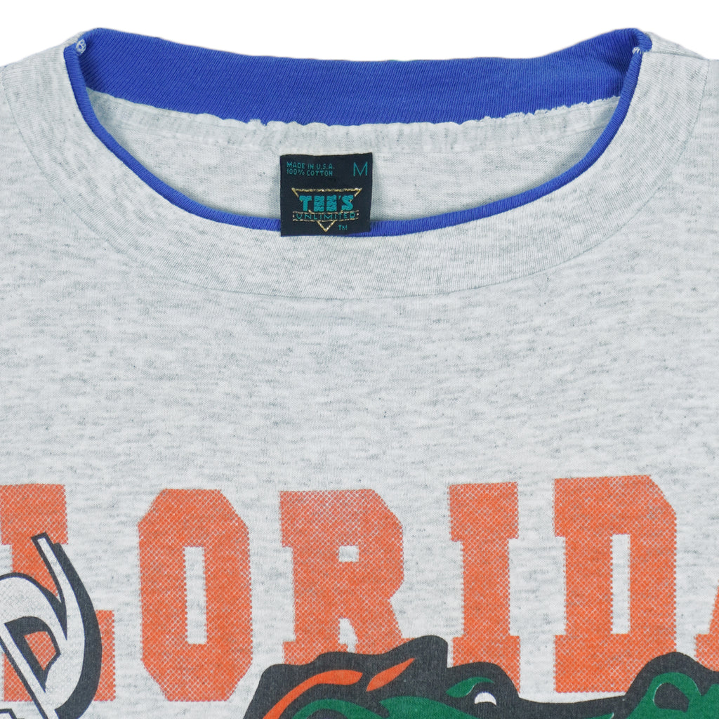 1990s vintage NCAA University of Florida Gators underlayer T-Shirt by Tee's Unlimited. Grey in color with blue sleeves, spell-out and logo on the front, Medium in size and is in excellent condition.