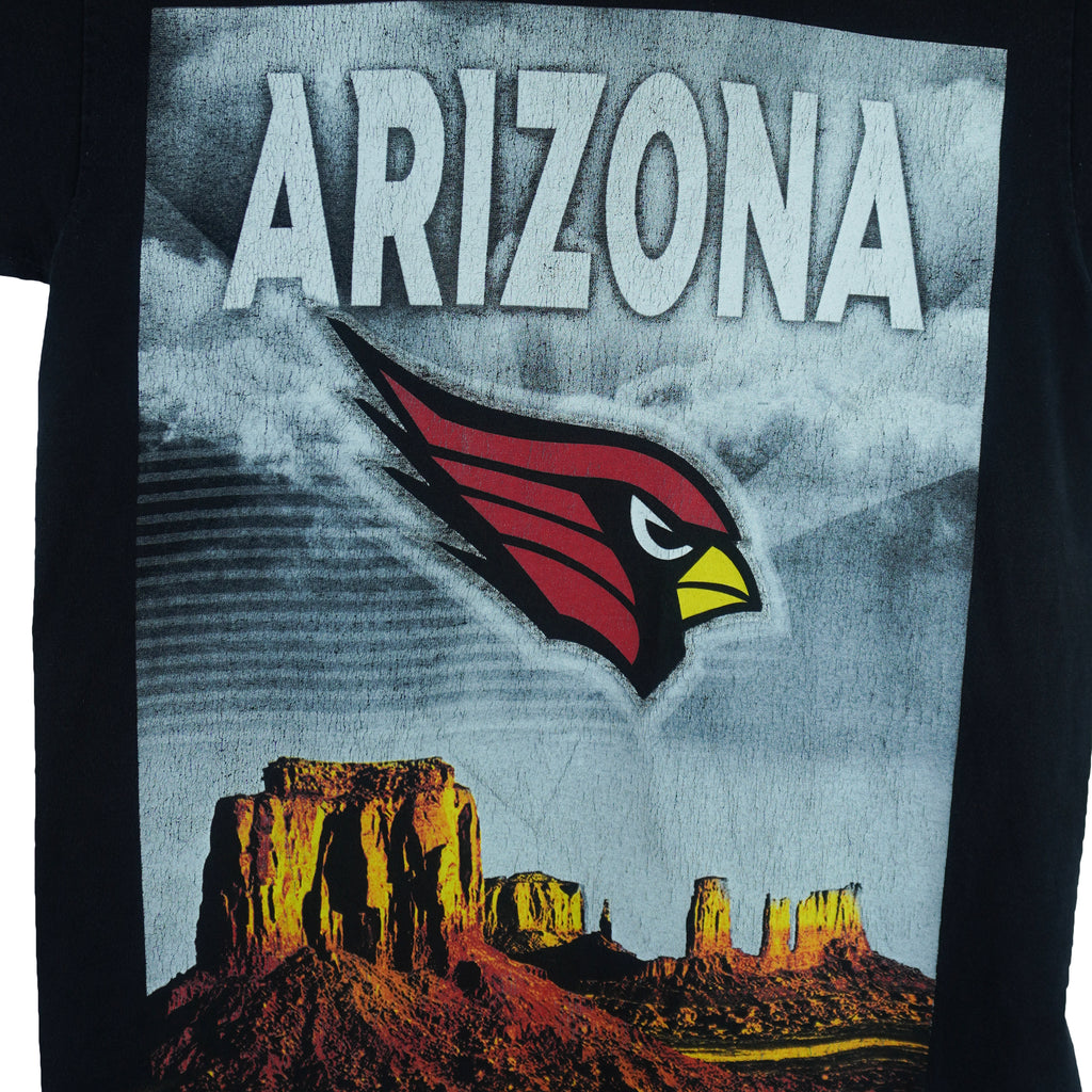 1990s vintage NFL Arizona Cardinals spell-out T-Shirt. Black in color with large full-screen print of the sandstone pillars in Monument Valley on front and "Arizona" text on back, fits Medium in size and is in excellent condition.