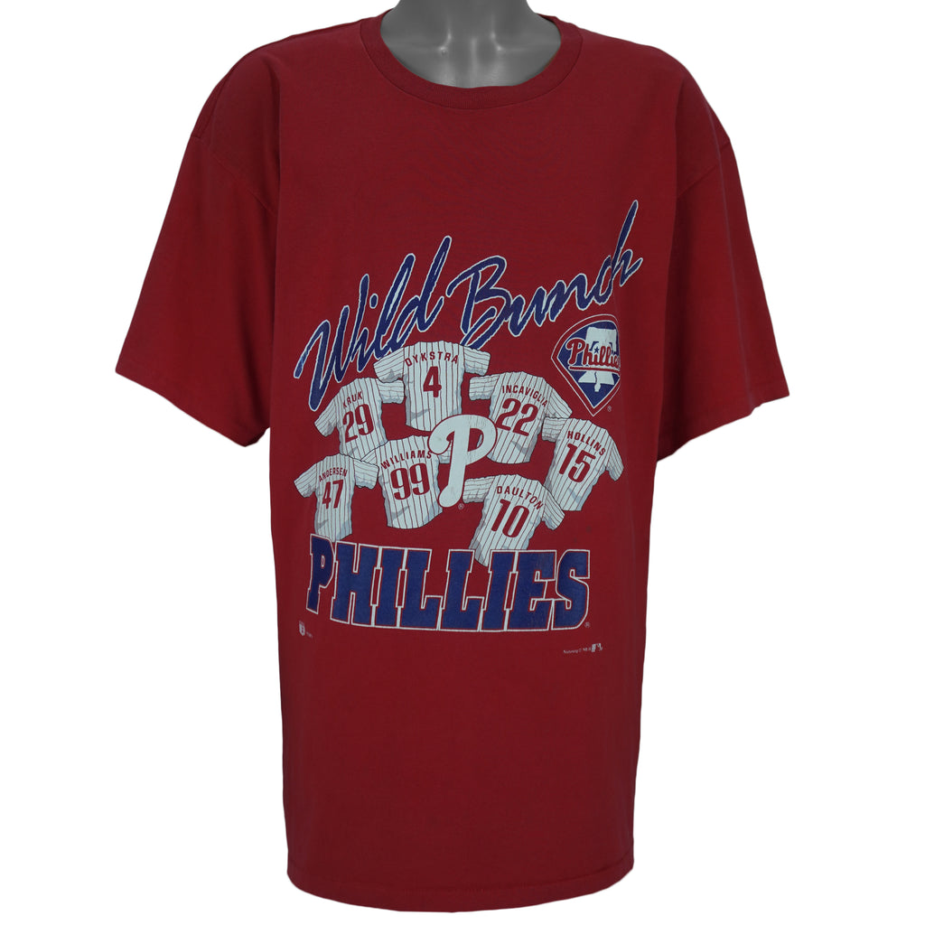 1990s vintage MLB Philadelphia Phillies spell-out T-Shirt by Nutmeg Mills (gold Athletic Dept tag). Red in color with graphic of 7 player jerseys and "Wild Bunch" text on front and is in good condition.