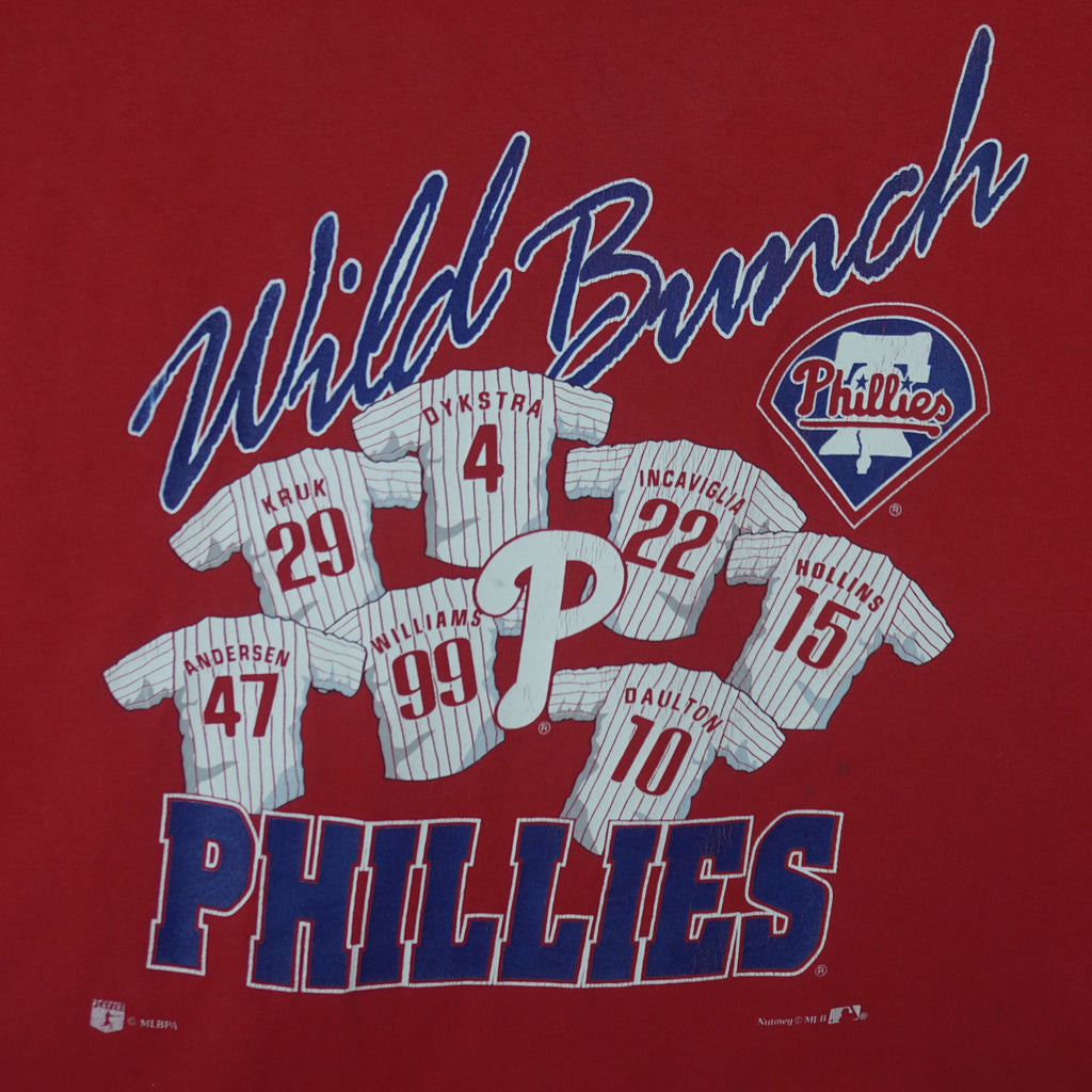 1990s vintage MLB Philadelphia Phillies spell-out T-Shirt by Nutmeg Mills (gold Athletic Dept tag). Red in color with graphic of 7 player jerseys and "Wild Bunch" text on front and is in good condition.